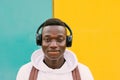 Young afro American black man listening music with wireless headphones while wearing a white sweatshirt and a backpack Royalty Free Stock Photo