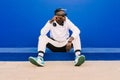 Young afro American black man wearing a white sweatshirt, basketball sneakers, sunglasses, comb in the hair and headphones Royalty Free Stock Photo