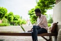 Young afro american female IT specialist working remotely on a new project using a public network wifi while sitting on a wooden b Royalty Free Stock Photo