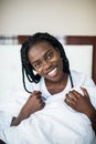 Young beautiful afro american girl smiling while lying in bed hugging pillow at home Royalty Free Stock Photo