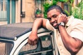 Young afro american guy speaking at mobile phone next old retro car - Black man smiling during phone conversation - Fashion with Royalty Free Stock Photo