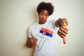 Young afro american man holding Serbia Serbian flag standing over isolated white background with angry face, negative sign showing Royalty Free Stock Photo