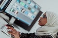 Young Afro-American modern Muslim businesswoman wearing a scarf in a creative bright office workplace with a big screen. Royalty Free Stock Photo