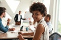 Young afro american woman is looking at camera and smiling while her boss standing near whiteboard and discussing Royalty Free Stock Photo