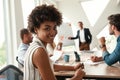 Young afro american woman is looking at camera and smiling while her boss standing near whiteboard and discussing Royalty Free Stock Photo