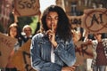 Young afro american woman with word power written on her face and with closed eyes showing silence sign while protesting