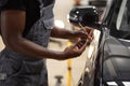 Young afro auto service worker is painting car details Royalty Free Stock Photo