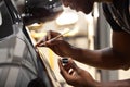 Young afro auto service worker is painting car details Royalty Free Stock Photo