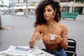 Young afro colombian woman sitting at cafe drinking coffee and reading newspaper Royalty Free Stock Photo