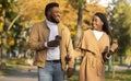 Young afro couple having coffee while walking in autumn park Royalty Free Stock Photo