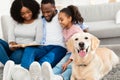 Young afro family reading book with dog at home Royalty Free Stock Photo