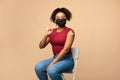 Young Afro lady in face mask showing okay gesture after covid-19 vaccine injection, recommending coronavius immunization