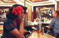 Young afro 1950s dressed woman at the bar counter of a aright carnival fair style bar at the Flight Cub, a vintage