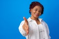 Young afro woman stretches hand for handshake against blue background Royalty Free Stock Photo