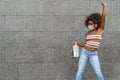 Young Afro woman wearing face mask dancing outdoor while listening to music with wireless headphones and vintage boombox Royalty Free Stock Photo