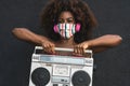 Young Afro woman wearing face mask dancing outdoor while listening to music with wireless headphones and vintage boombox Royalty Free Stock Photo