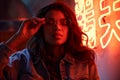 Young Afro woman wears trendy glasses stands in red neon sign night club light.