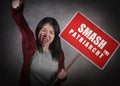 Young aggressive ultra feminist Asian Korean woman holding protest billboard with smash the patriarchy text standing for women