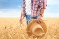 Young agronomist with straw hat in grain field