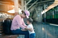 Young Aian mother playing with her little infant kids while waiting for the train on train platform. Both are happy and laughing Royalty Free Stock Photo