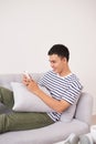 Young aisan man sitting relaxed on sofa with smartphone checking