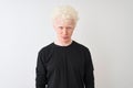 Young albino blond man wearing black t-shirt standing over isolated white background depressed and worry for distress, crying Royalty Free Stock Photo