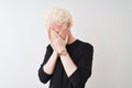 Young albino blond man wearing black t-shirt standing over isolated white background with sad expression covering face with hands Royalty Free Stock Photo