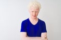 Young albino blond man wearing blue casual t-shirt standing over isolated white background skeptic and nervous, disapproving