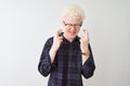 Young albino blond man wearing casual shirt and glasses over isolated white background gesturing finger crossed smiling with hope Royalty Free Stock Photo
