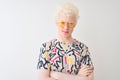 Young albino blond man wearing colorful t-shirt and sunglasses over isolated red background skeptic and nervous, disapproving Royalty Free Stock Photo