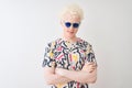 Young albino blond man wearing colorful t-shirt and sunglasses over isolated red background skeptic and nervous, disapproving Royalty Free Stock Photo