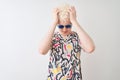 Young albino blond man wearing colorful t-shirt and sunglasses over isolated red background suffering from headache desperate and Royalty Free Stock Photo