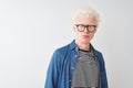 Young albino blond man wearing denim shirt and glasses over isolated white background depressed and worry for distress, crying Royalty Free Stock Photo