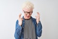 Young albino blond man wearing denim shirt and glasses over isolated white background gesturing finger crossed smiling with hope Royalty Free Stock Photo