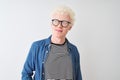 Young albino blond man wearing denim shirt and glasses over isolated white background smiling looking to the side and staring away Royalty Free Stock Photo