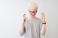 Young albino blond man wearing striped t-shirt and glasses over isolated white background gesturing finger crossed smiling with Royalty Free Stock Photo