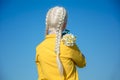 A young albino woman in yellow is standing with her back to the camera, a bunch of daisies on her shoulder. against the Royalty Free Stock Photo