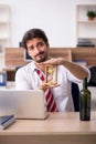 Young alcohol addicted male employee in time management concept