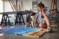 Young alluring female artist playing with her dog