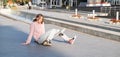 Young alternative teenager girl skater sitting on board on the city street looking away. Royalty Free Stock Photo