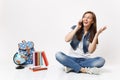 Young amazed woman student talking on mobile phone looking aside spreading hands sitting near globe, backpack, school Royalty Free Stock Photo