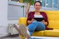 Young American business woman sitting at her sofa, using tablet in her office and smiling Royalty Free Stock Photo