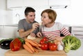 Young American couple working at home kitchen preparing vegetable salad together smiling happy Royalty Free Stock Photo