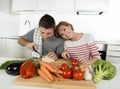 Young American couple working at home kitchen preparing vegetable salad together smiling happy Royalty Free Stock Photo