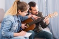 guitar tutor explaining basics to his female client at home