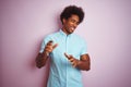 Young american man with afro hair wearing blue shirt standing over isolated pink background disgusted expression, displeased and Royalty Free Stock Photo