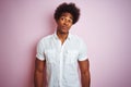 Young american man with afro hair wearing white shirt standing over isolated pink background smiling looking to the side and Royalty Free Stock Photo