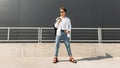 Young American man model in stylish clothes in sunglasses in red leather sandals with a vintage black bag stands Royalty Free Stock Photo