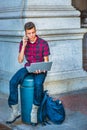 Young American Man working on laptop computer, talking on cell p Royalty Free Stock Photo