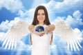 Young angel woman holding Earth in hands with clouds